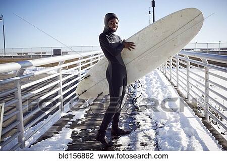 Black teenage girl in wetsuit carrying surfboard in winter View Large Photo Image Stock Image - Black teenage girl in wetsuit carrying surfboard in winter. Fotosearch