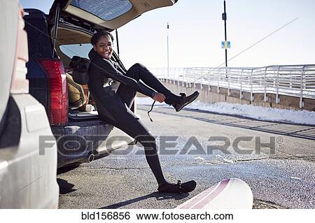 Stock Photograph - Black teenage girl putting on wetsuit. Fotosearch