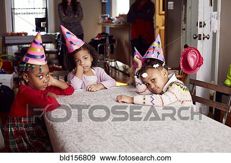 Bored children wearing party hats at table View Large Photo Image Stock Photo - Bored children wearing party hats at table. Fotosearch