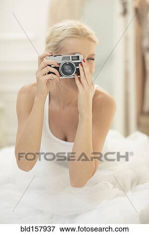 Bride photographing with vintage camera on bed View Large Photo Image Stock Photo - Bride photographing with vintage camera on bed. Fotosearch