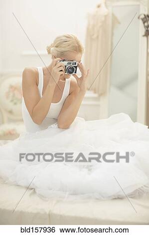 Bride photographing with vintage camera on bed View Large Photo Image Stock Photograph - Bride photographing with vintage camera on bed. Fotosearch