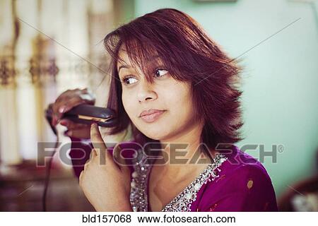 Brunette woman straightening her hair View Large Photo Image Stock Photo - Brunette woman straightening her hair. Fotosearch