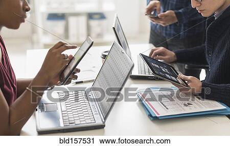 Stock Image - Business people using technology in office. Fotosearch