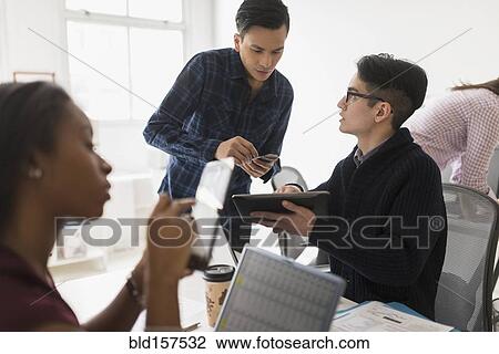 Stock Image - Business people using technology in office. Fotosearch