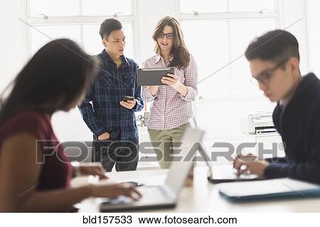 Stock Image - Business people using technology in office. Fotosearch