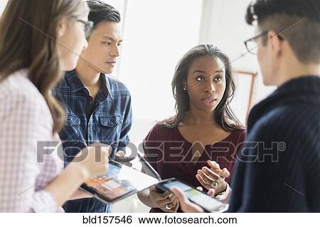 Stock Photograph - Business people working together in office with technology. Fotosearch