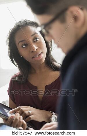 Stock Photo - Businesswoman and colleague using digital tablet in office. Fotosearch