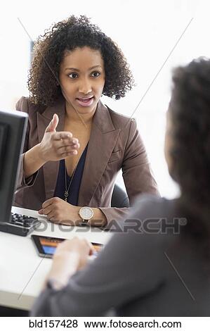 Stock Photo - Businesswomen talking in office meeting. Fotosearch
