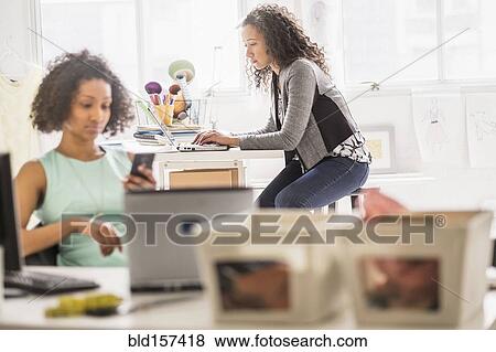 Businesswomen working at desks in office View Large Photo Image Stock Photo - Businesswomen working at desks in office. Fotosearch