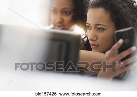 Stock Photograph - Businesswomen working with cell phone and computer. Fotosearch