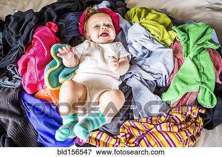 Stock Photo - Caucasian baby girl laying in pile of laundry. Fotosearch