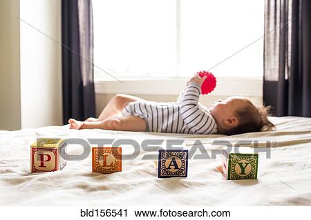 Stock Image - Caucasian baby girl playing on bed. Fotosearch