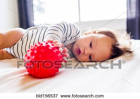 Stock Photo - Caucasian baby girl playing on bed. Fotosearch