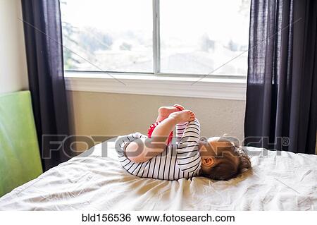 Caucasian baby girl playing on bed View Large Photo Image Stock Photograph - Caucasian baby girl playing on bed. Fotosearch