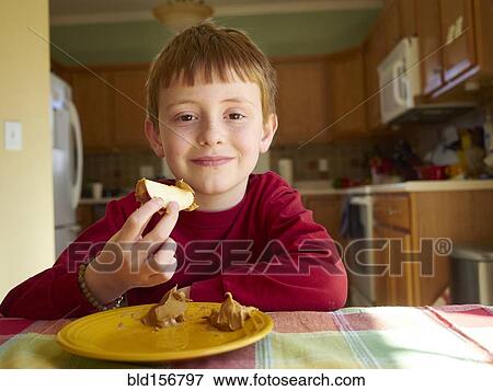 Stock Photo - Caucasian boy eating apple with peanut butter snack. Fotosearch
