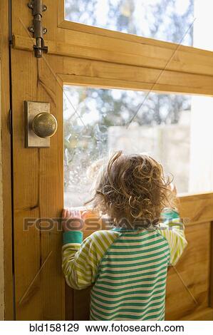 Stock Photo - Caucasian boy looking out door window. Fotosearch