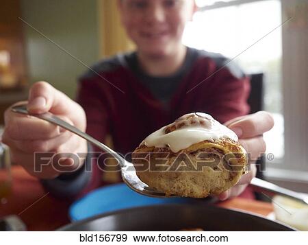 Caucasian boy showing cinnamon bun View Large Photo Image Stock Photo - Caucasian boy showing cinnamon bun. Fotosearch