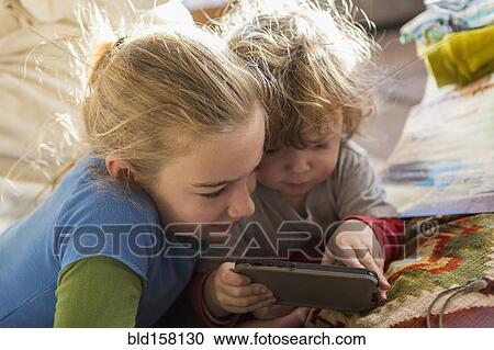 Caucasian brother and sister using cell phone on sofa View Large Photo Image Stock Image - Caucasian brother and sister using cell phone on sofa. Fotosearch