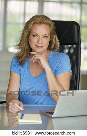Stock Image - Caucasian businesswoman smiling at office desk. Fotosearch