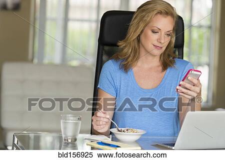 Stock Photography - Caucasian businesswoman texting at breakfast. Fotosearch