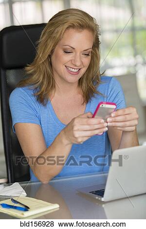 Stock Photo - Caucasian businesswoman texting on cell phone. Fotosearch