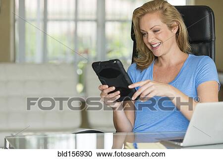Stock Image - Caucasian businesswoman using digital tablet at office desk. Fotosearch
