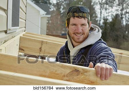 Picture - Caucasian carpenter building house extension in winter. Fotosearch