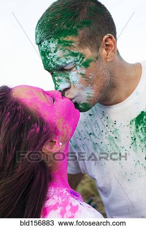Stock Image - Caucasian couple splattered with paint powder kissing. Fotosearch