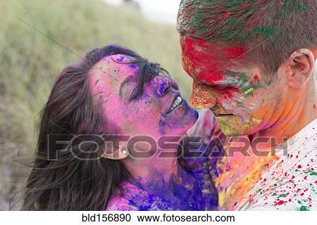 Stock Image - Caucasian couple splattered with paint powder. Fotosearch