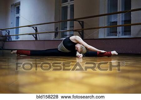 Stock Photo - Caucasian dancer stretching doing splits on studio floor. Fotosearch