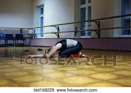 Stock Photo - Caucasian dancer stretching on studio floor. Fotosearch