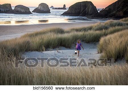 Stock Image - Caucasian girl carrying lantern on beach. Fotosearch