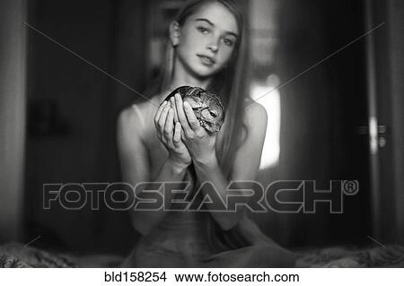 Picture - Caucasian girl holding pet chinchilla on bed. Fotosearch