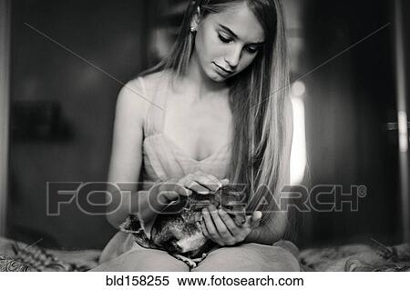 Stock Photography - Caucasian girl holding pet chinchilla on bed. Fotosearch