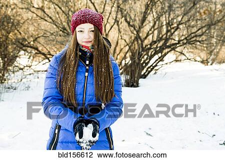 Stock Image - Caucasian girl holding snow in field. Fotosearch
