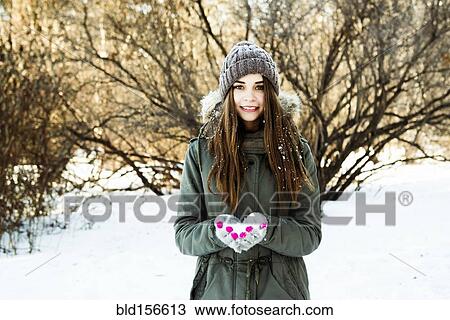 Stock Image - Caucasian girl holding snow in field. Fotosearch