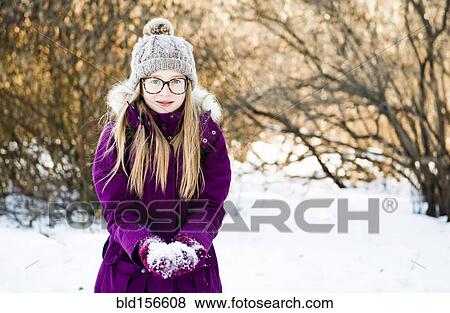 Stock Photo - Caucasian girl holding snow in field. Fotosearch