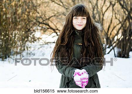 Stock Photography - Caucasian girl holding snow in field. Fotosearch