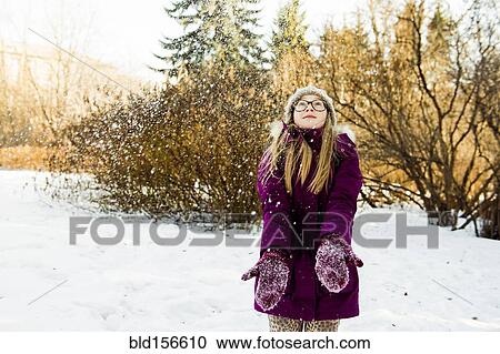 Stock Image - Caucasian girl looking up in snowy field. Fotosearch