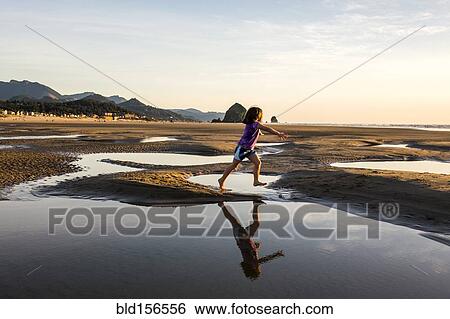 Caucasian girl running in tide pools on beach, Cannon Beach, Oregon, United States View Large Photo Image Stock Photograph - Caucasian girl running in tide pools on beach, Cannon Beach, Oregon, United States. Fotosearch