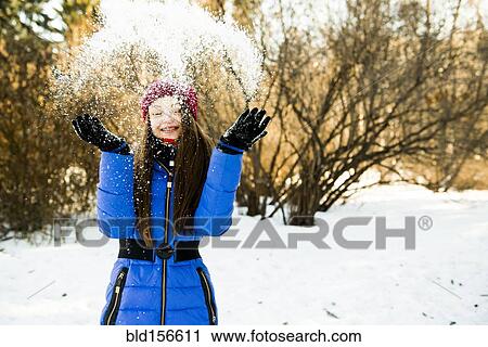 Stock Image - Caucasian girl throwing snow field. Fotosearch