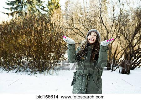 Picture - Caucasian girl throwing snow in field. Fotosearch