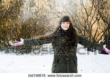 Stock Photograph - Caucasian girl throwing snow in field. Fotosearch