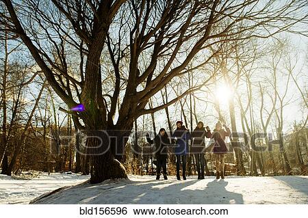 Stock Photograph - Caucasian girls standing neat tree in snowy field. Fotosearch