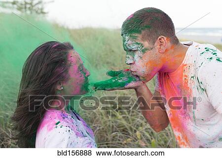 Stock Photo - Caucasian man blowing paint powder on girlfriend. Fotosearch