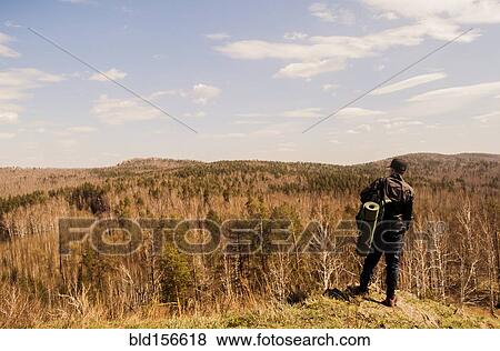Caucasian man with camping gear overlooking rural forest View Large Photo Image Stock Photo - Caucasian man with camping gear overlooking rural forest. Fotosearch