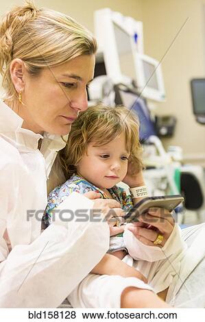 Caucasian mother and son texting on cell phone in hospital View Large Photo Image Stock Photo - Caucasian mother and son texting on cell phone in hospital. Fotosearch
