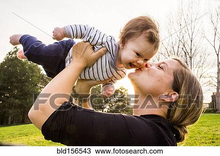 Stock Image - Caucasian mother kissing baby girl outdoors. Fotosearch
