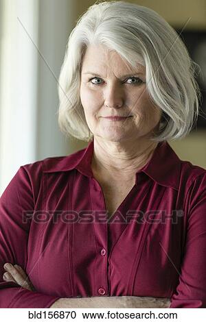 Stock Image - Caucasian older woman smiling with arms crossed. Fotosearch