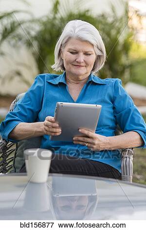 Caucasian older woman using digital tablet in backyard View Large Photo Image Stock Photo - Caucasian older woman using digital tablet in backyard. Fotosearch